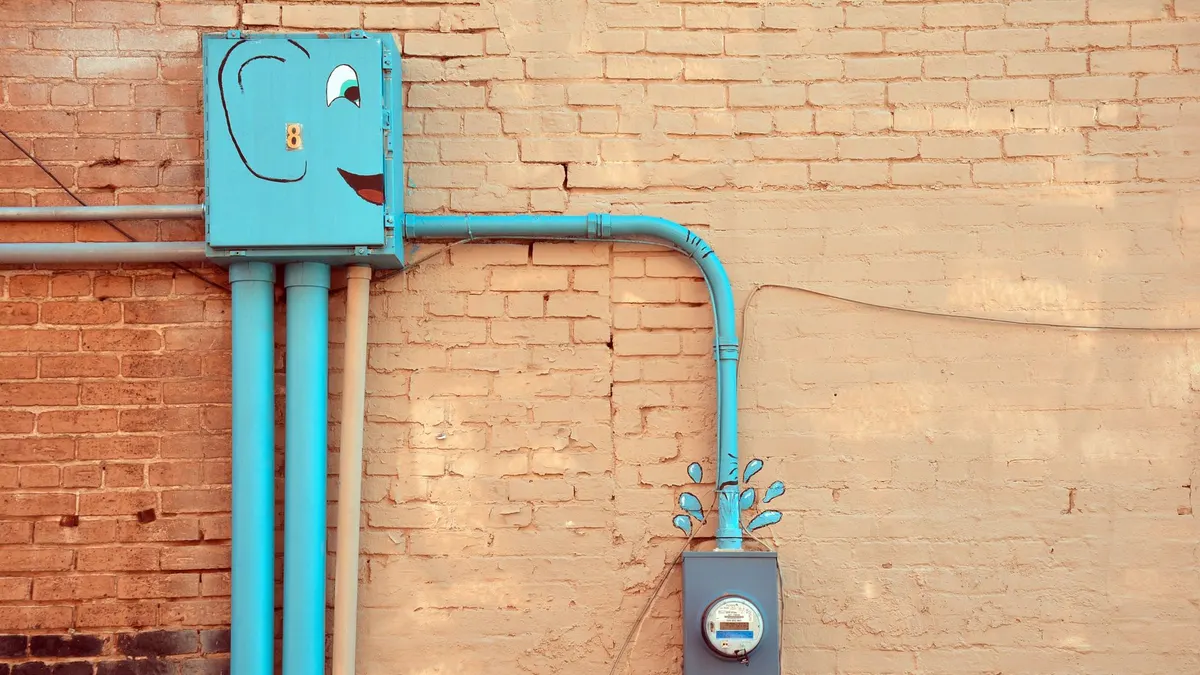 A quirky outdoor scene featuring painted utility meters and piping on a brick wall in Texarkana, Texas.