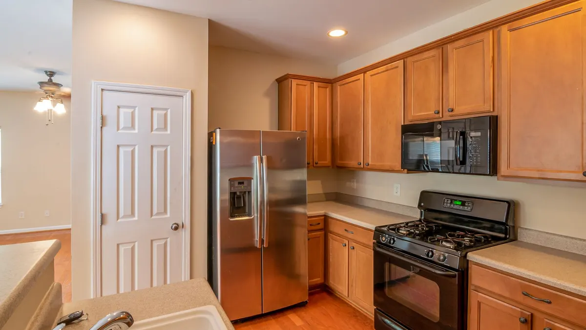 Contemporary kitchen featuring wooden cabinets, stainless steel refrigerator, and modern appliances.
