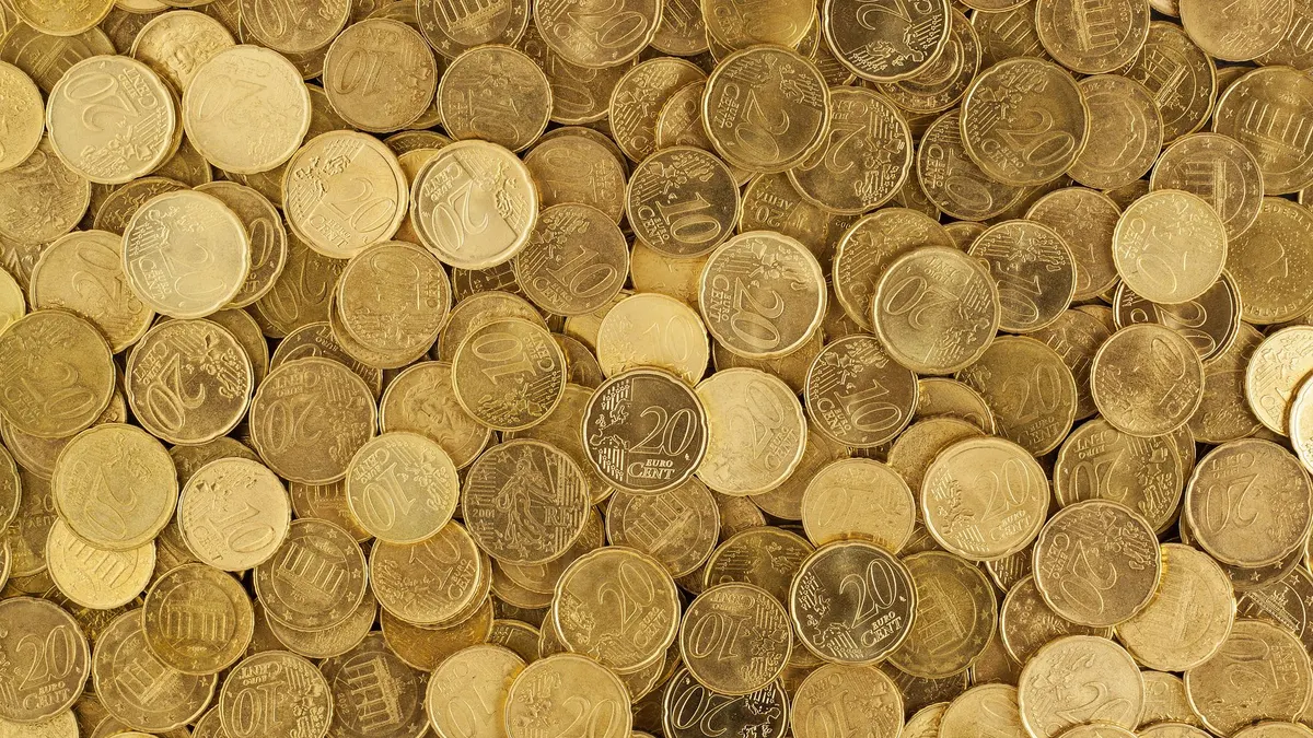 A close-up shot of Euro coins scattered in a pile, showcasing a rich golden texture.
