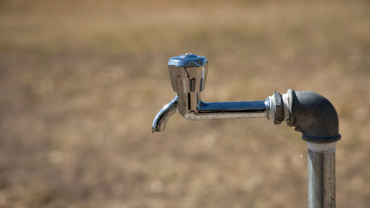 Close-up of a metal water faucet in an outdoor setting, highlighting its rustic charm and simplicity.