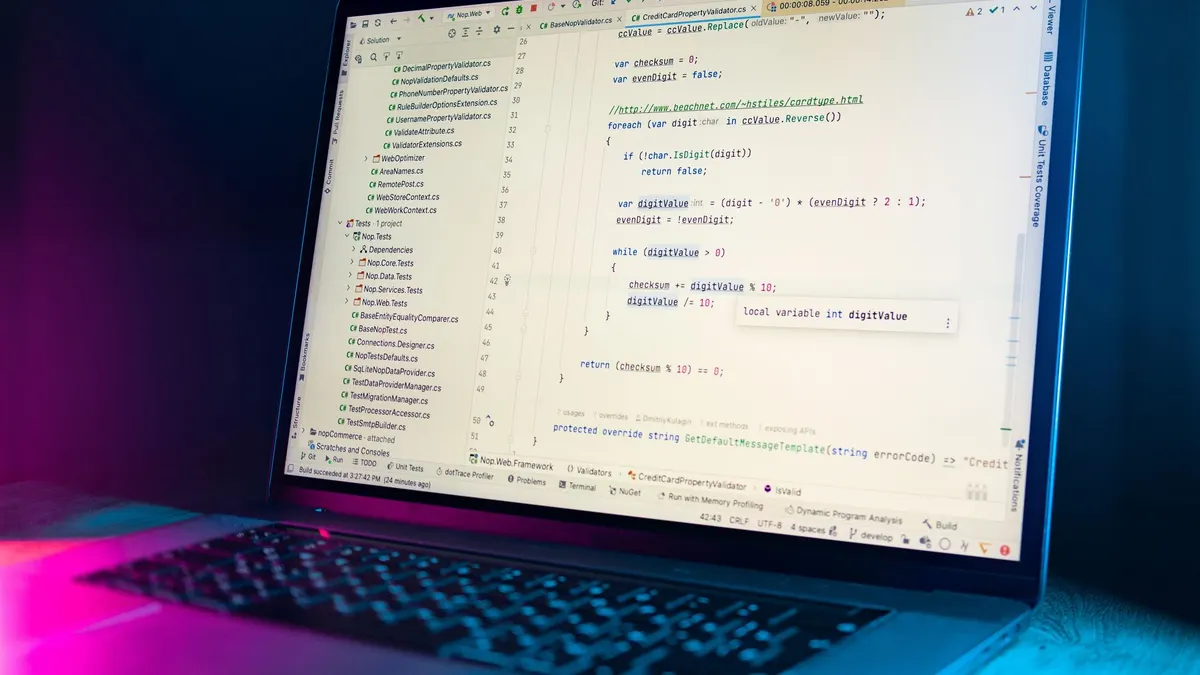 A laptop screen showing a code editor with visible programming code in a dimly lit environment.