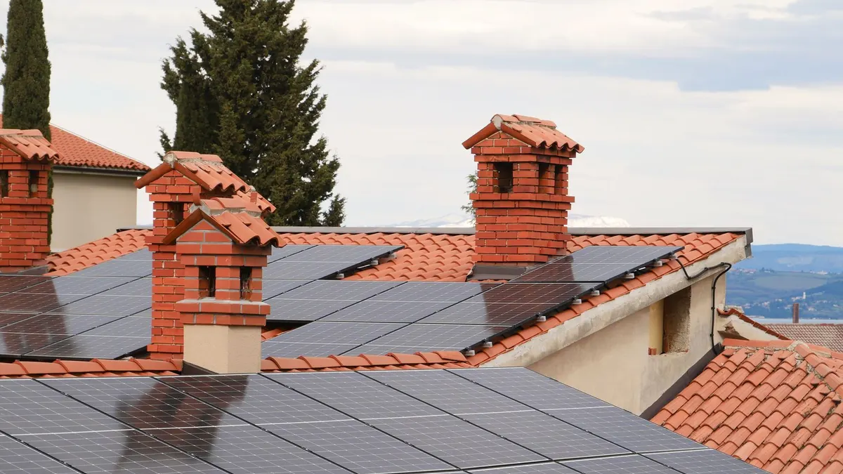 Solar panels on tiled roofs of houses with chimneys, capturing clean energy.