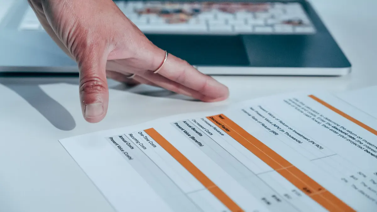 Close-up of a hand reviewing a financial report on a laptop, indicating focus on business analysis.