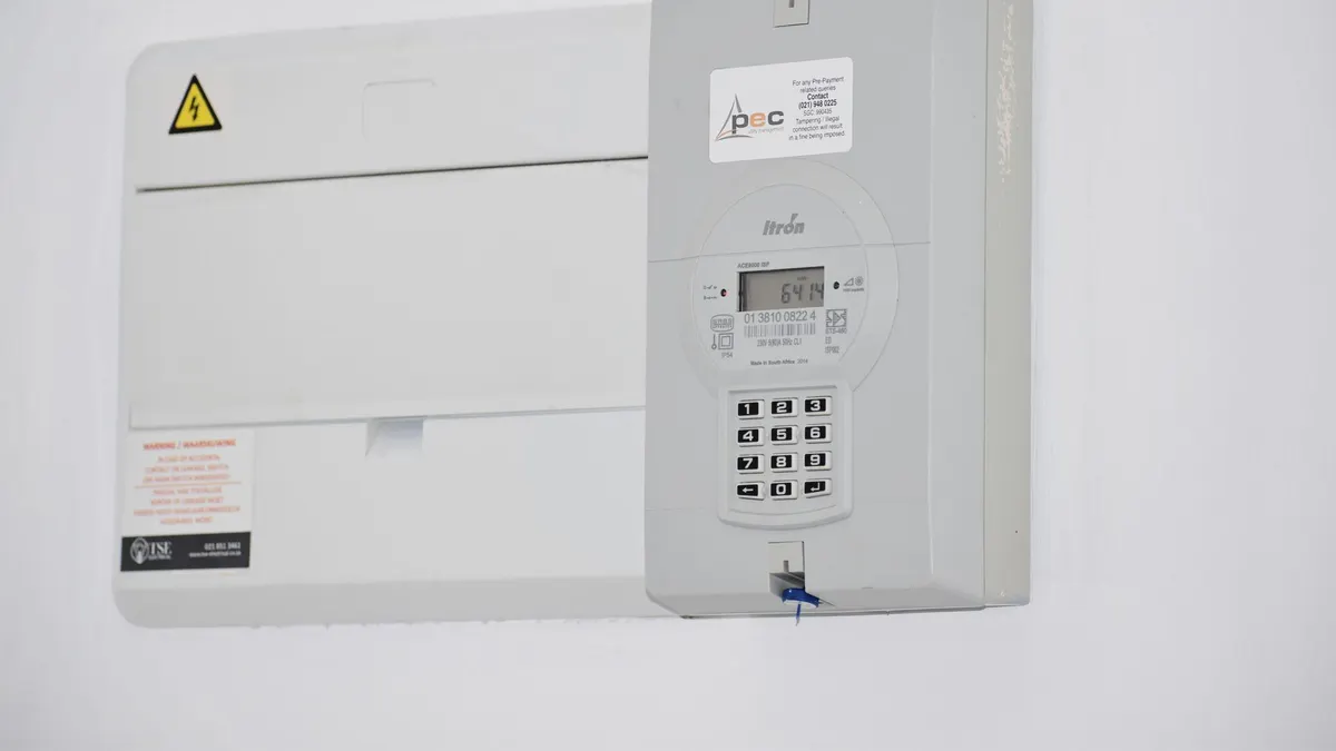 Electrical meter and fuse box on a white wall in Cape Town, South Africa, for energy monitoring or billing.