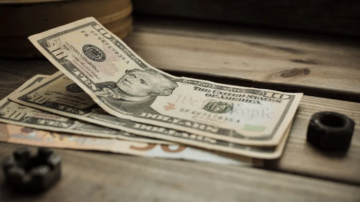 A stack of US dollar bills on a rustic wooden table close-up view.