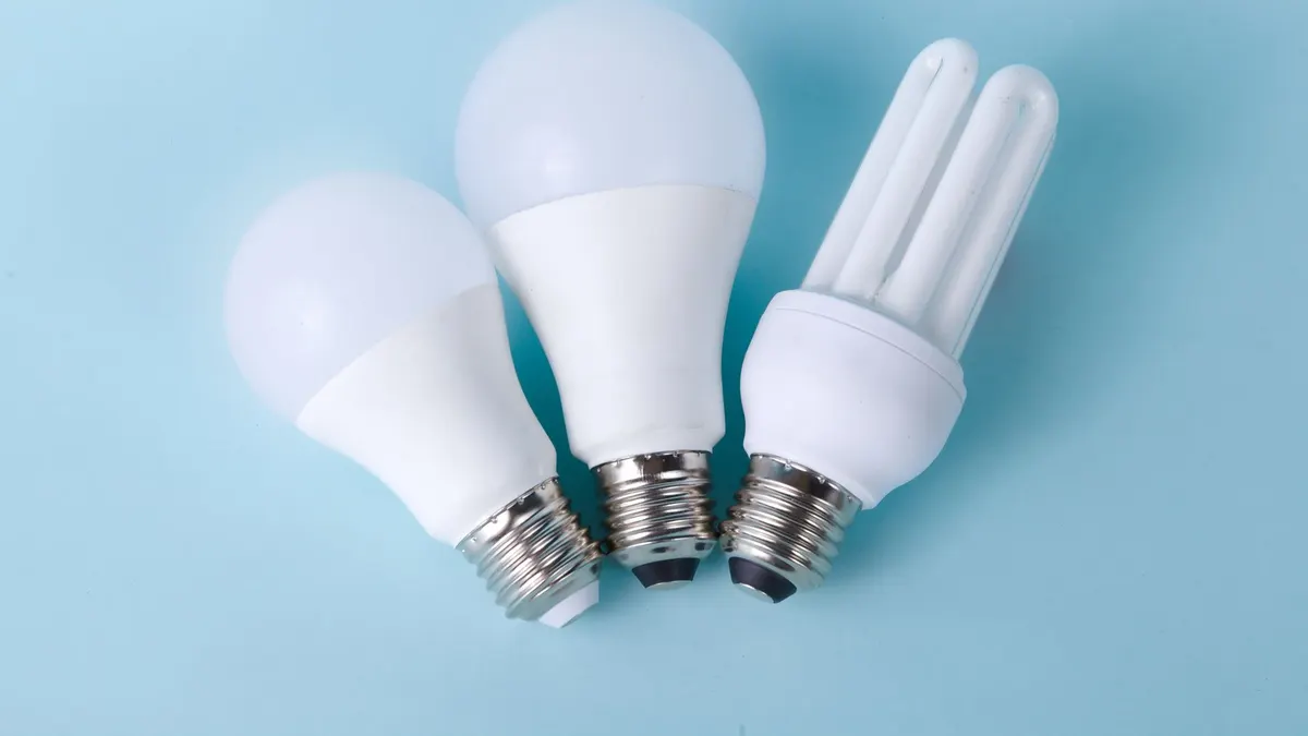 Three assorted LED and CFL light bulbs against a light blue background.