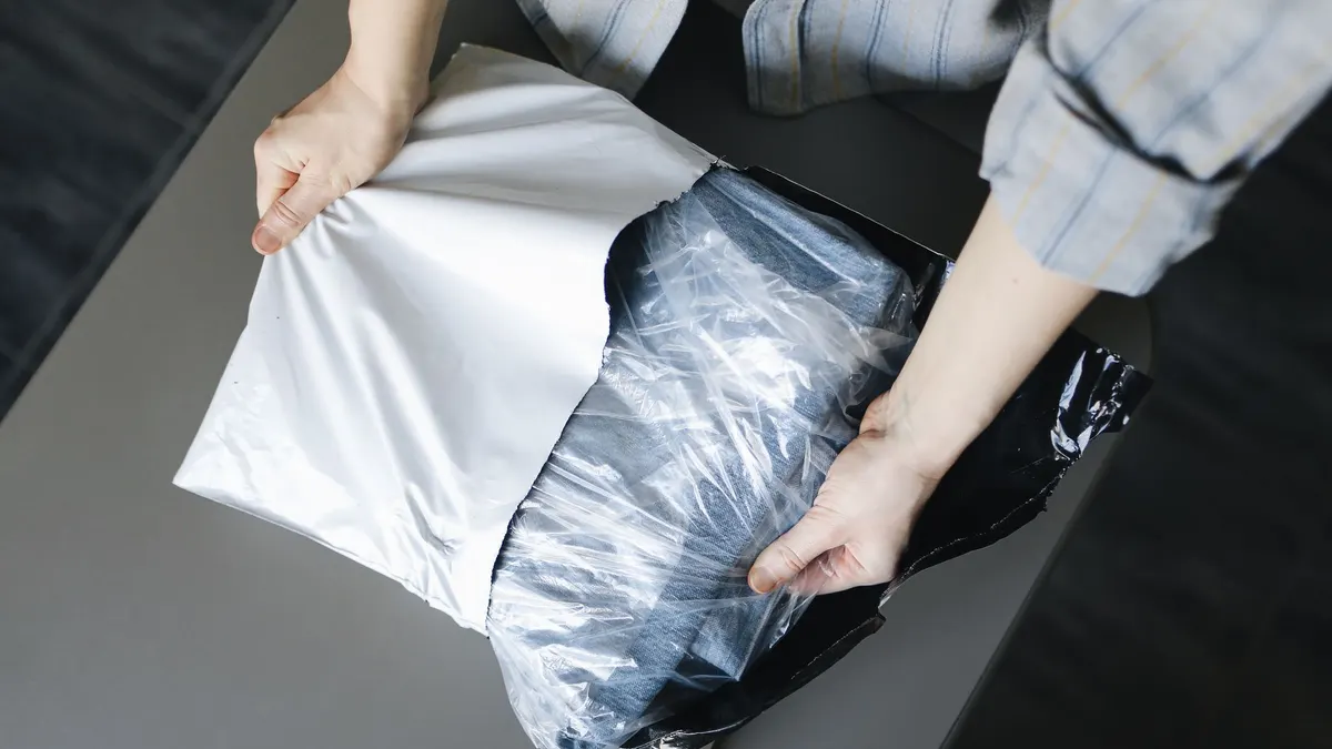 Close-up of a person unpacking a delivered parcel on a table indoors.