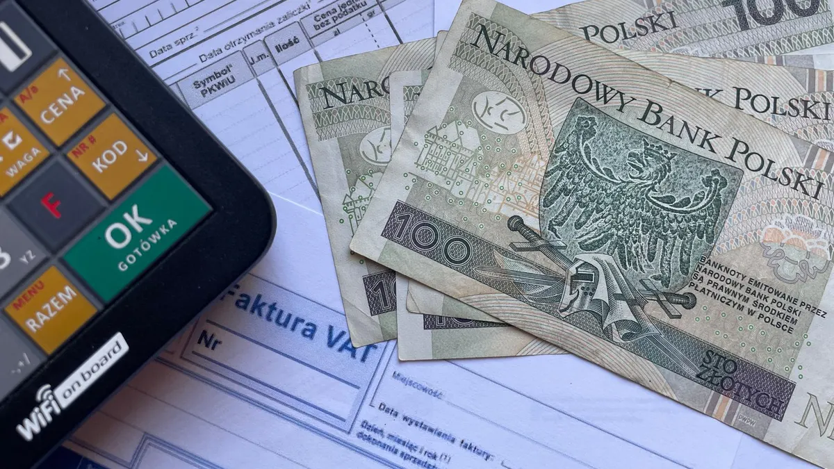 Polish currency placed on invoices with a calculator, illustrating financial transactions or budgeting.