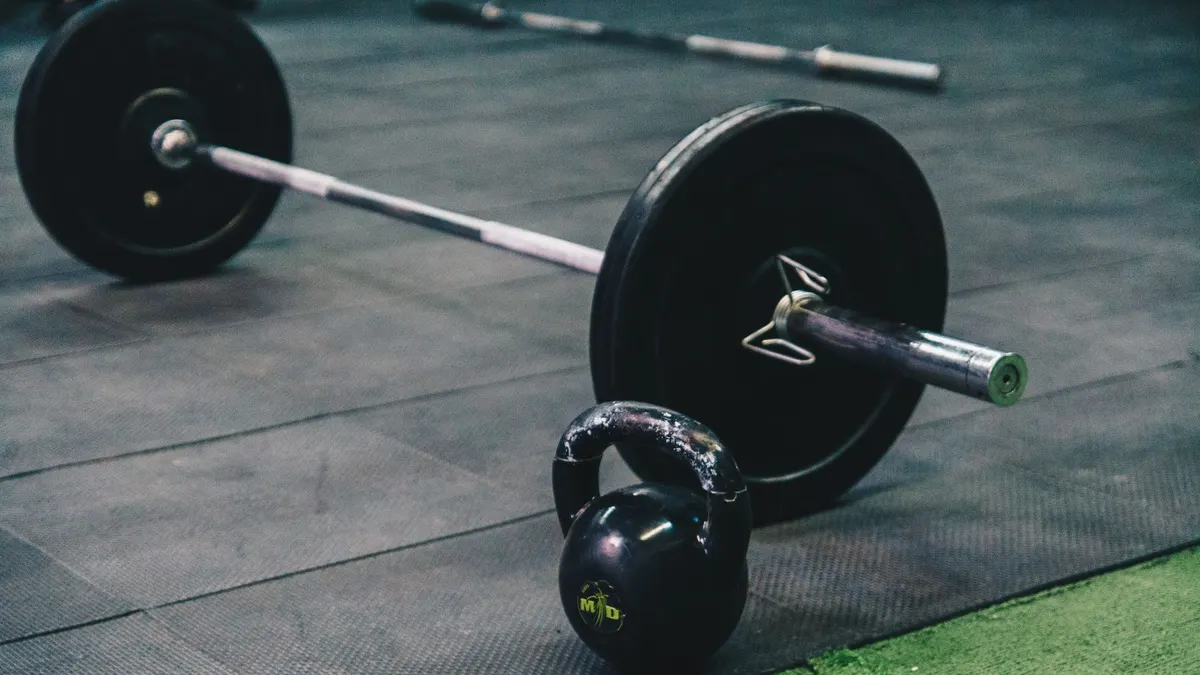 Barbell and kettlebell on gym floor, ideal for fitness and strength training themes.