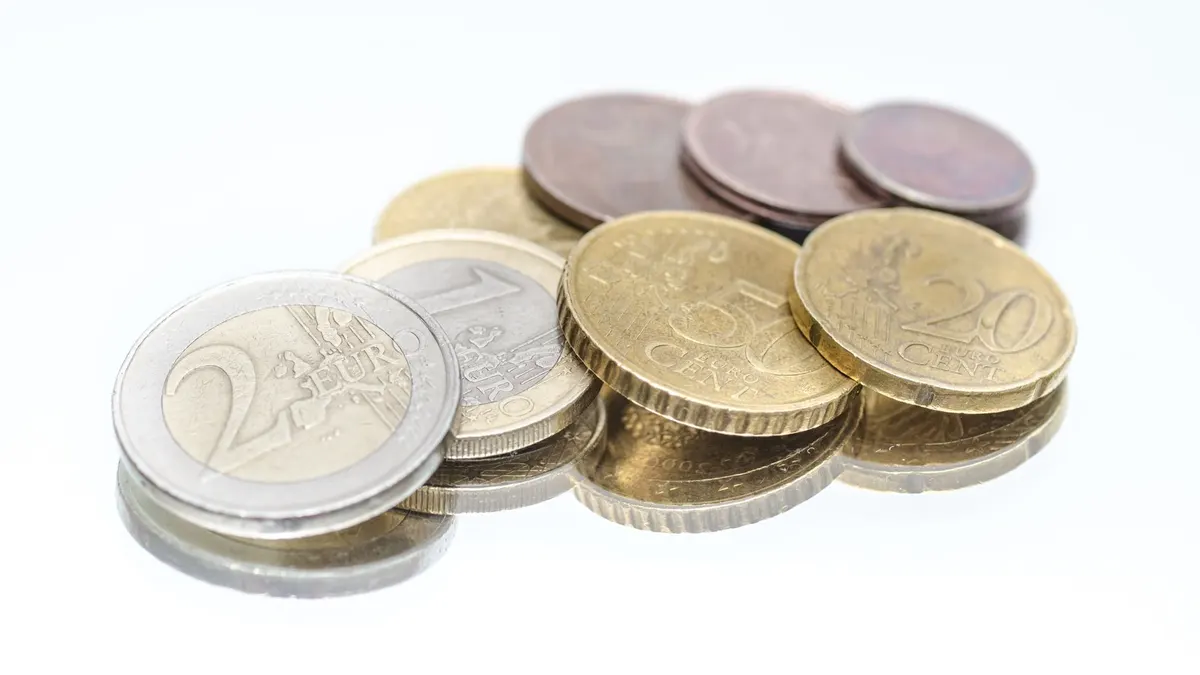 Close-up of Euro coins in different denominations placed on a shiny reflective surface.
