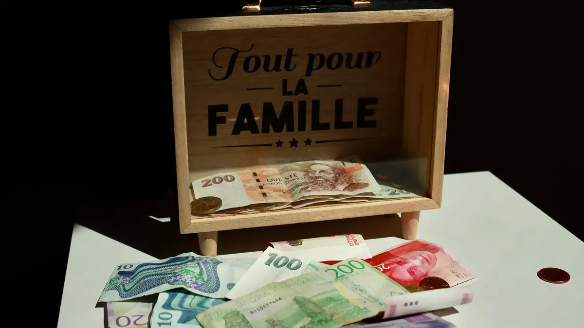 A wooden box with money and 'Tout pour la Famille' text, symbolizing family savings.