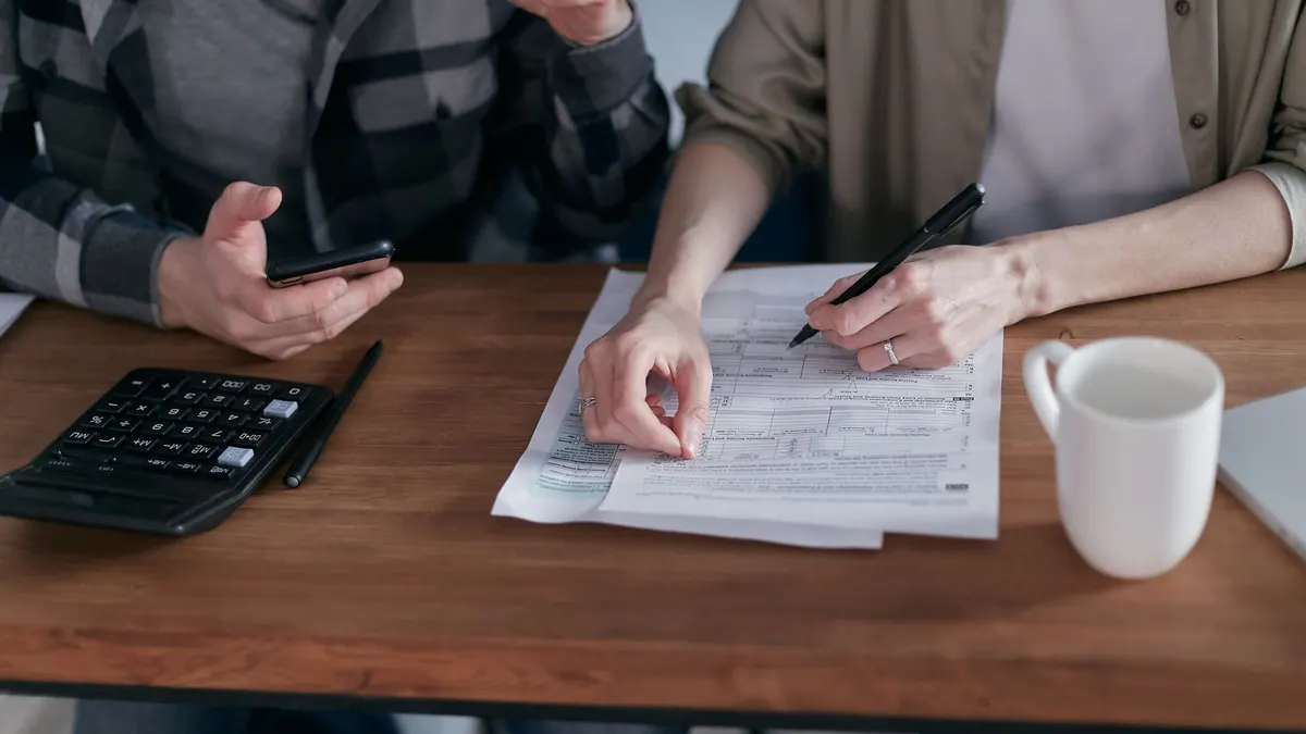 A couple collaboratively managing finances with papers and calculator in hand.