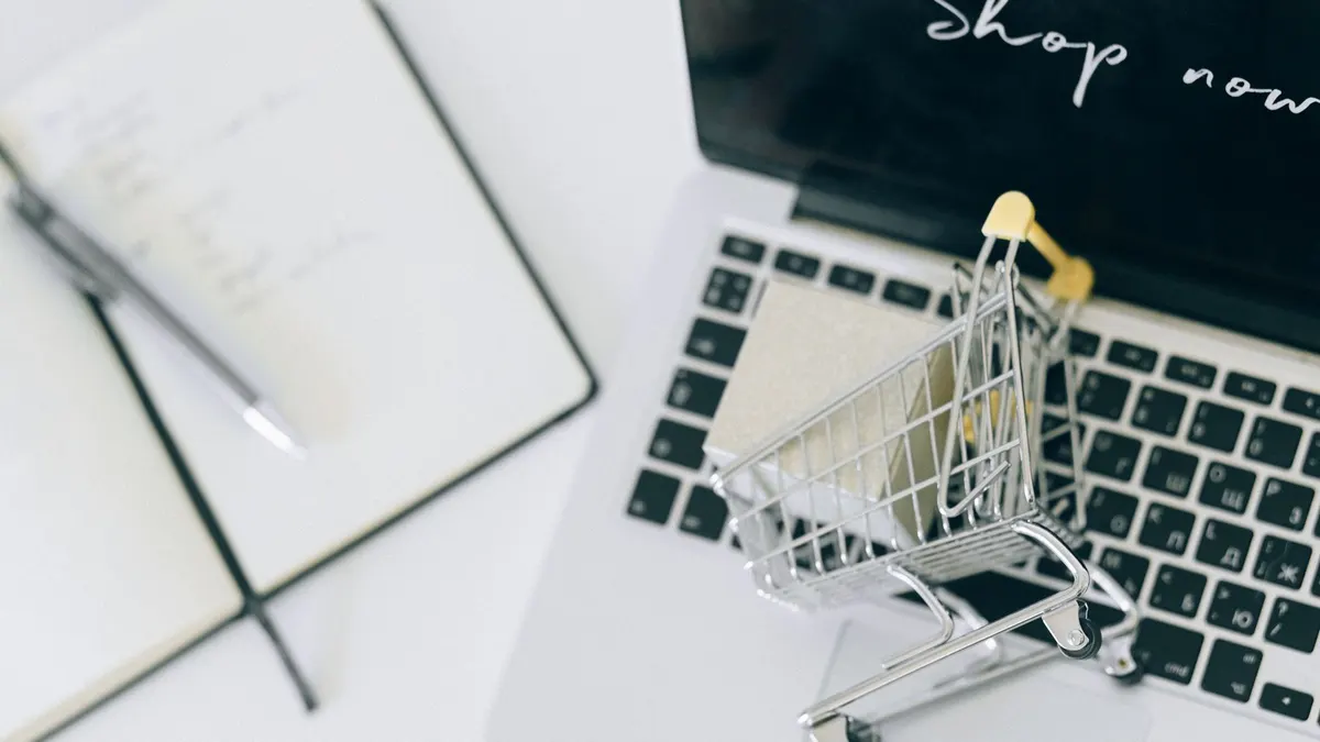 Creative depiction of online shopping with a miniature cart on a laptop keyboard.