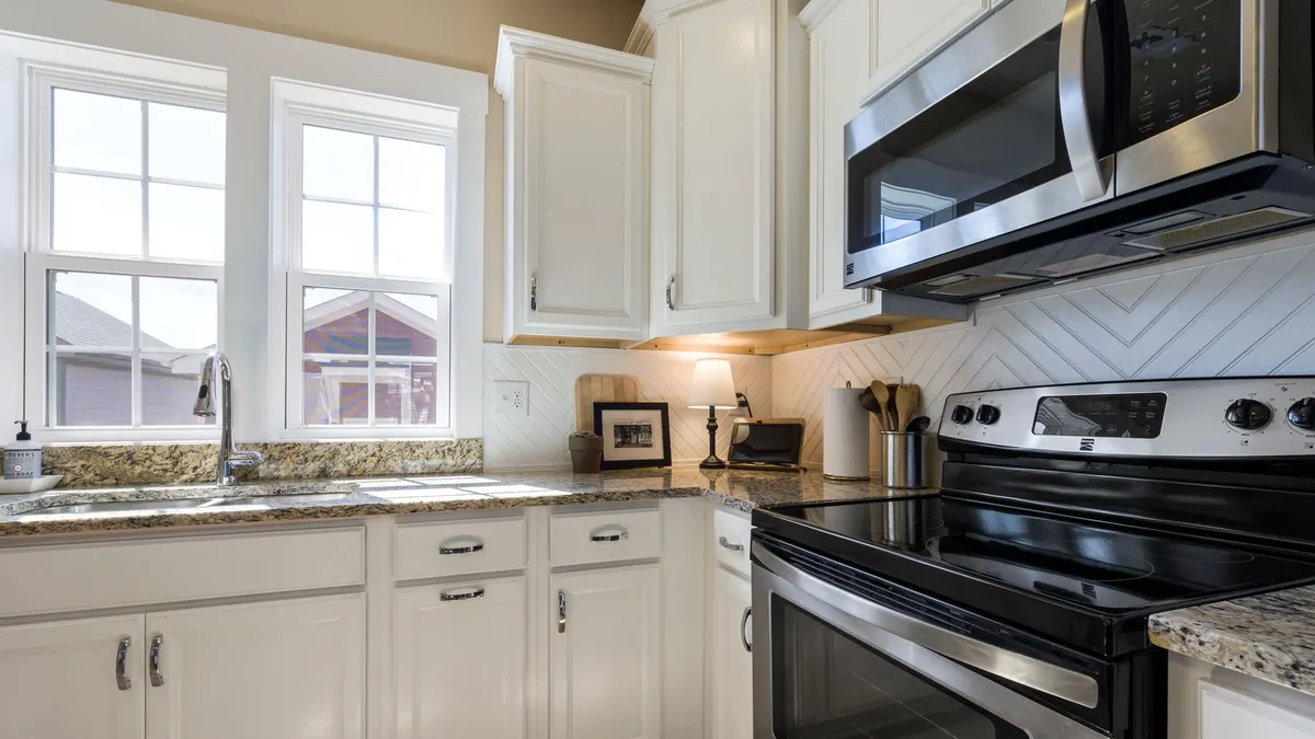 Bright and stylish modern kitchen featuring white cabinets and granite countertops with stainless steel appliances.