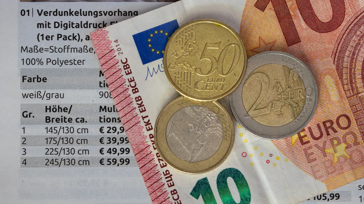 Euro coins and bills on a price list, symbolizing finance and economy.