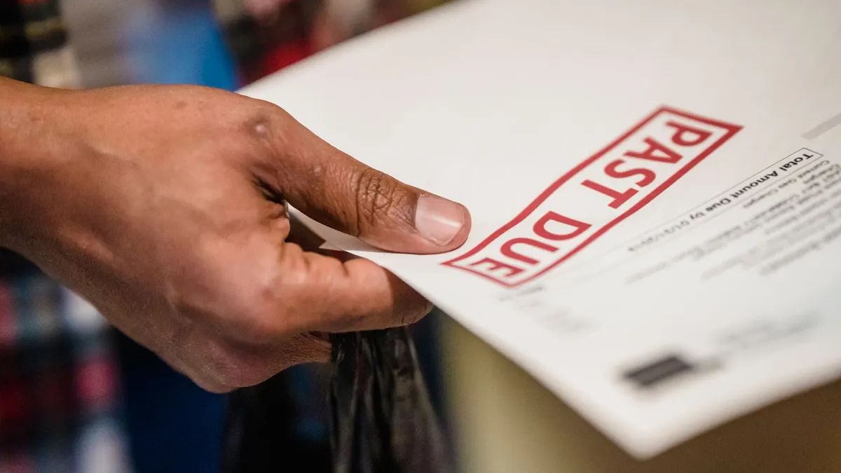 A close-up of a hand holding a document with a 'Past Due' stamp, highlighting financial urgency.