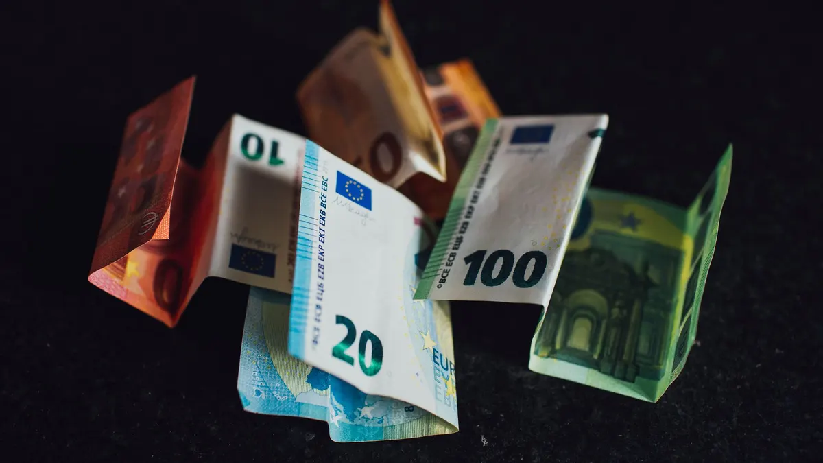 Assorted Euro banknotes in denominations of 10, 20, and 100 on a dark surface, highlighting European currency.