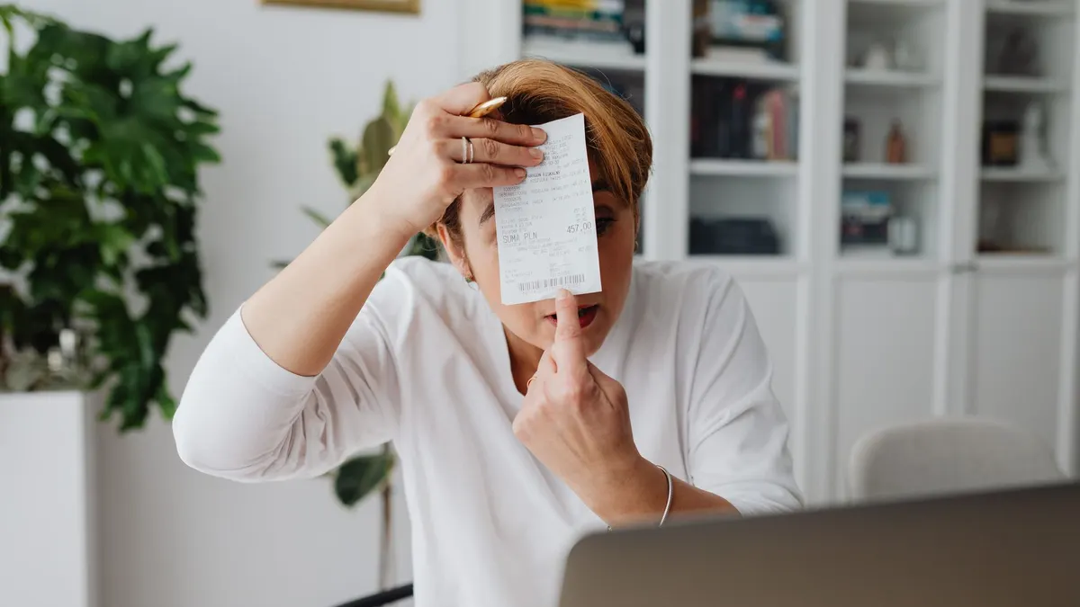 Businesswoman showing a receipt during a home office work session, highlighting technology integration.