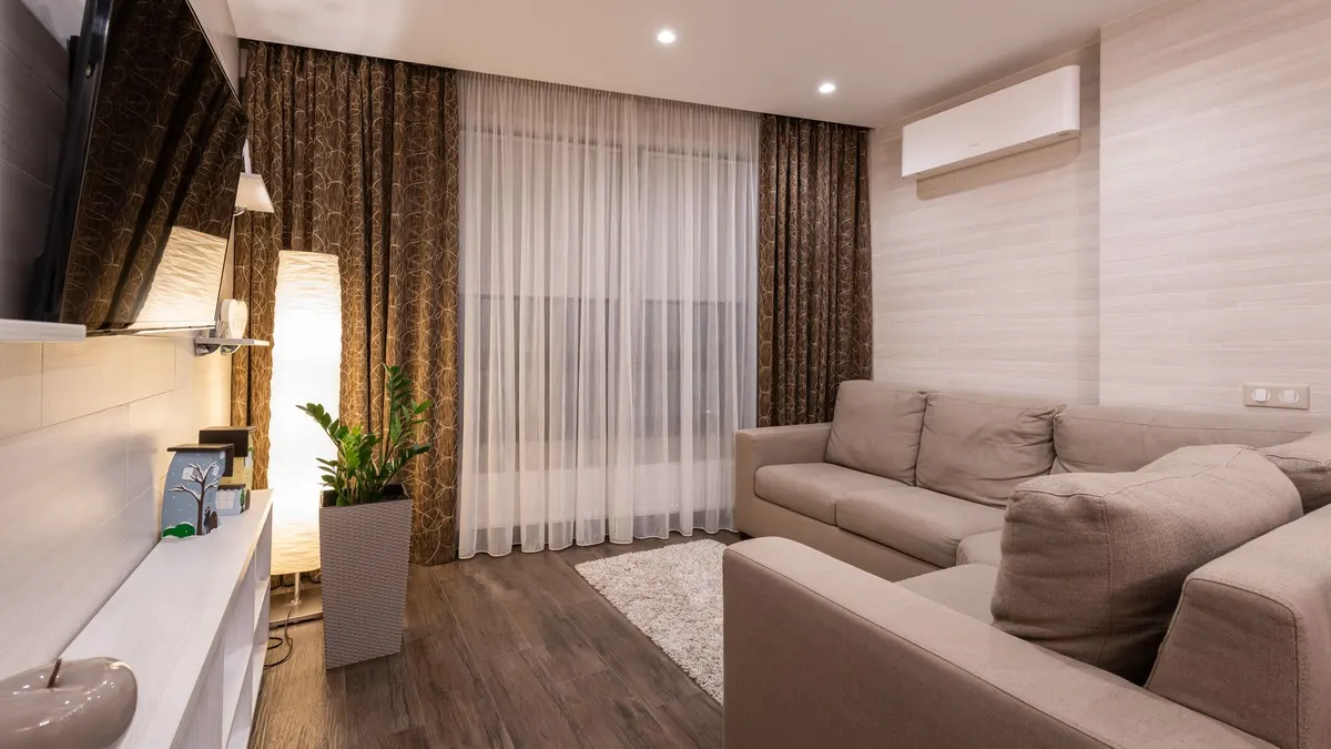 A stylish and cozy living room featuring a sofa, wooden flooring, and soft lighting.