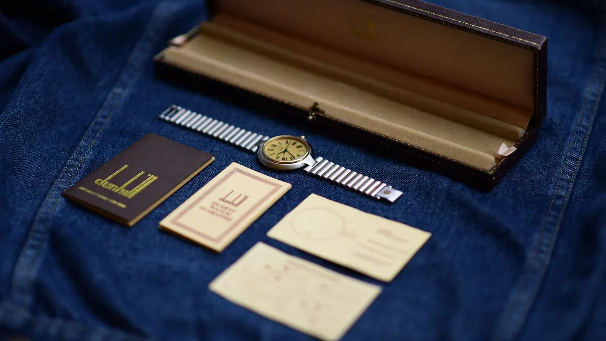 Elegant wristwatch displayed on denim fabric with packaging and accessories, showcasing luxury and style.