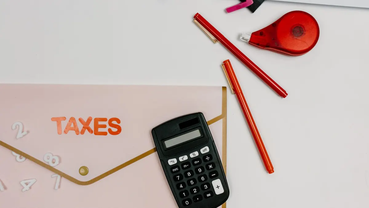 Flat lay image featuring a calculator, pens, and a folder labeled 'TAXES', perfect for finance-related themes.