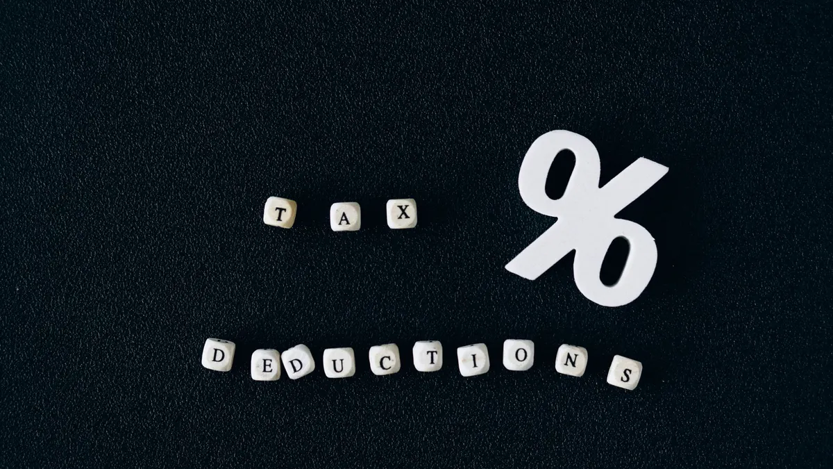 Conceptual image of tax deductions with alphabet blocks and percent symbol on black surface.