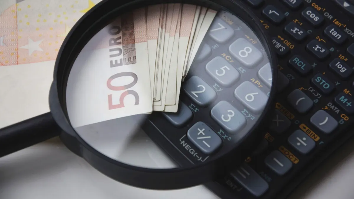 Euro bills under magnifying glass with calculator, symbolizing finance and analysis.