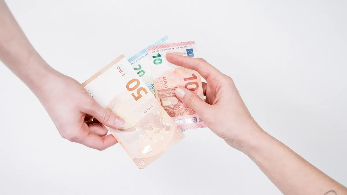 Close-up of hands exchanging euro banknotes, symbolizing financial transactions and currency exchange.