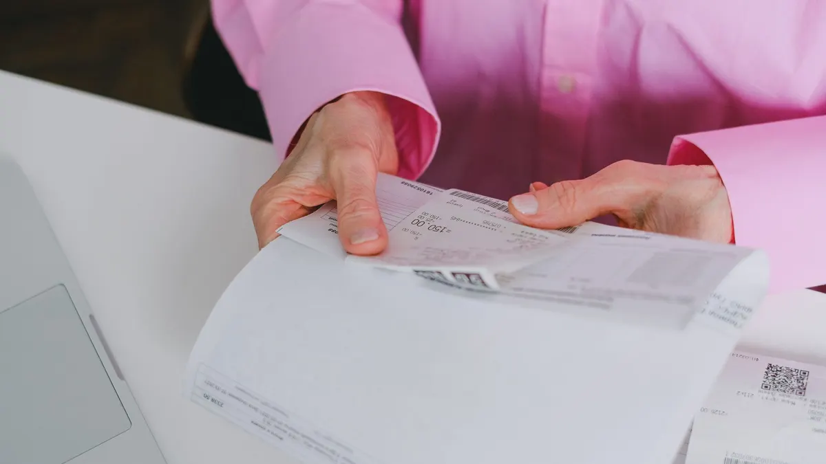 Business person handling paper receipts, meticulously organized.