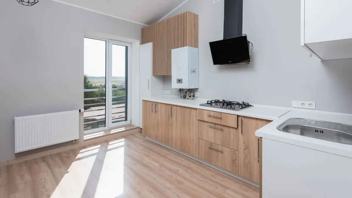 Stylish empty kitchen with wooden cabinets and large windows.