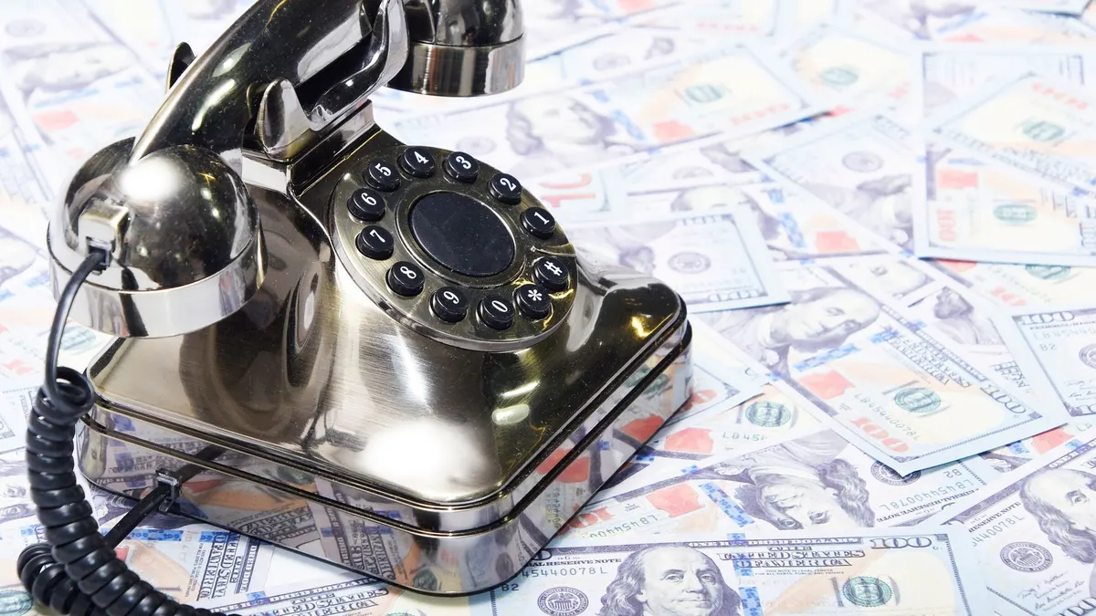 Vintage telephone set on a stack of US dollar bills, symbolizing wealth and communication.