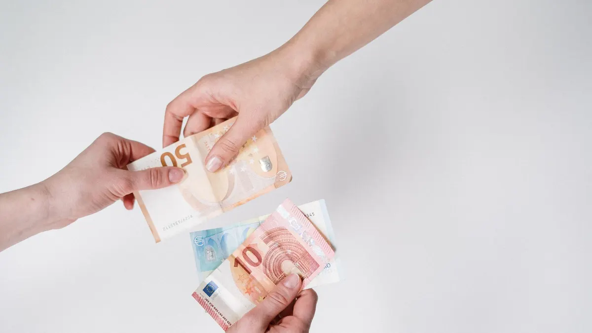 Close-up of hands exchanging euro bills, symbolizing finance and transaction.