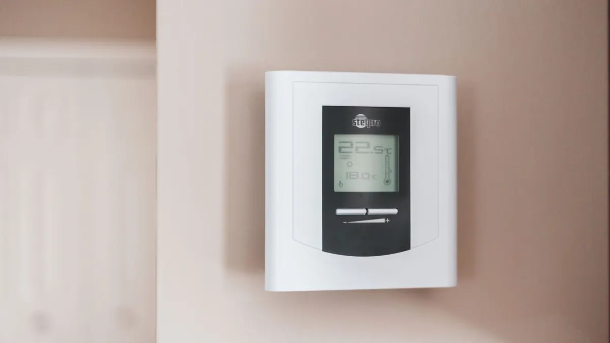 Close-up of a modern digital thermostat mounted on a wall, displaying temperature settings in Celsius.