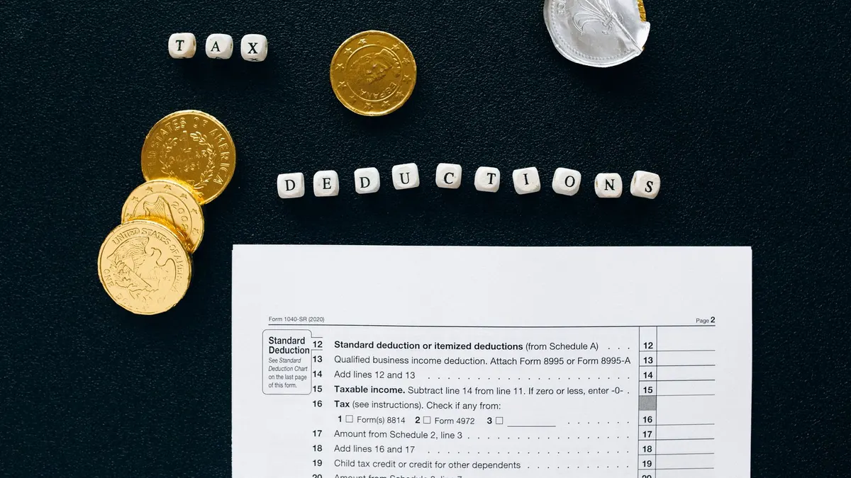 Image of tax deductions concept with coins and tax form on black background.